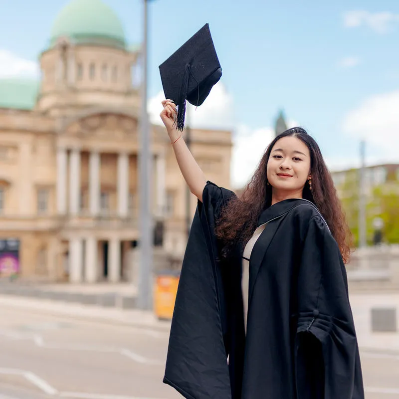 A University of Hull Graduate in cap and gown outside city hall in Hull