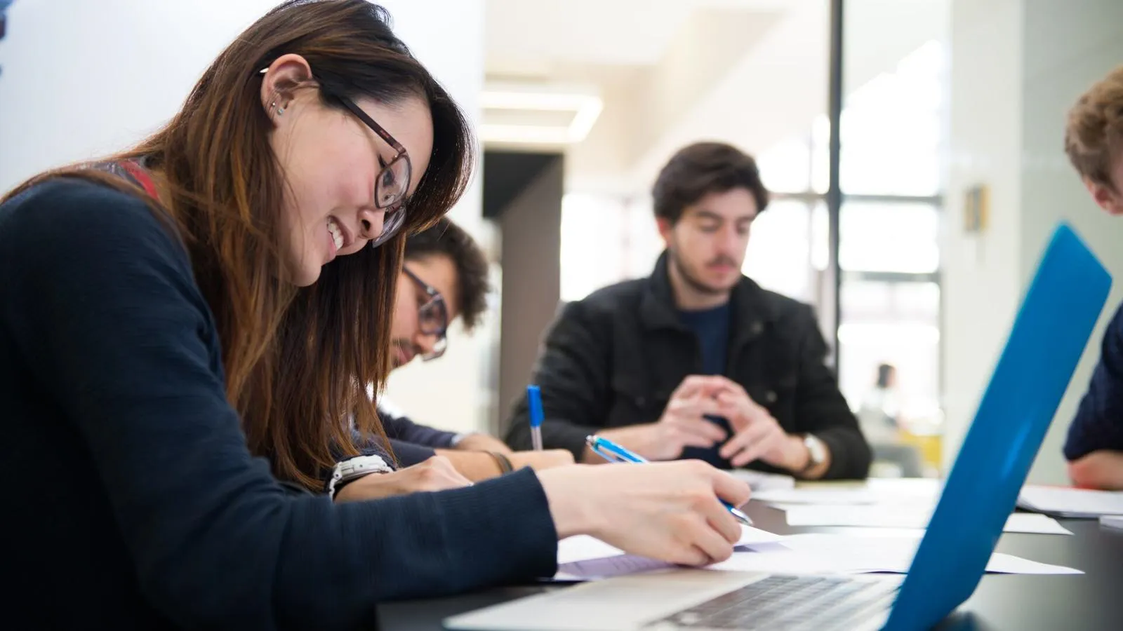 Masters students in front of laptop while working in university library
