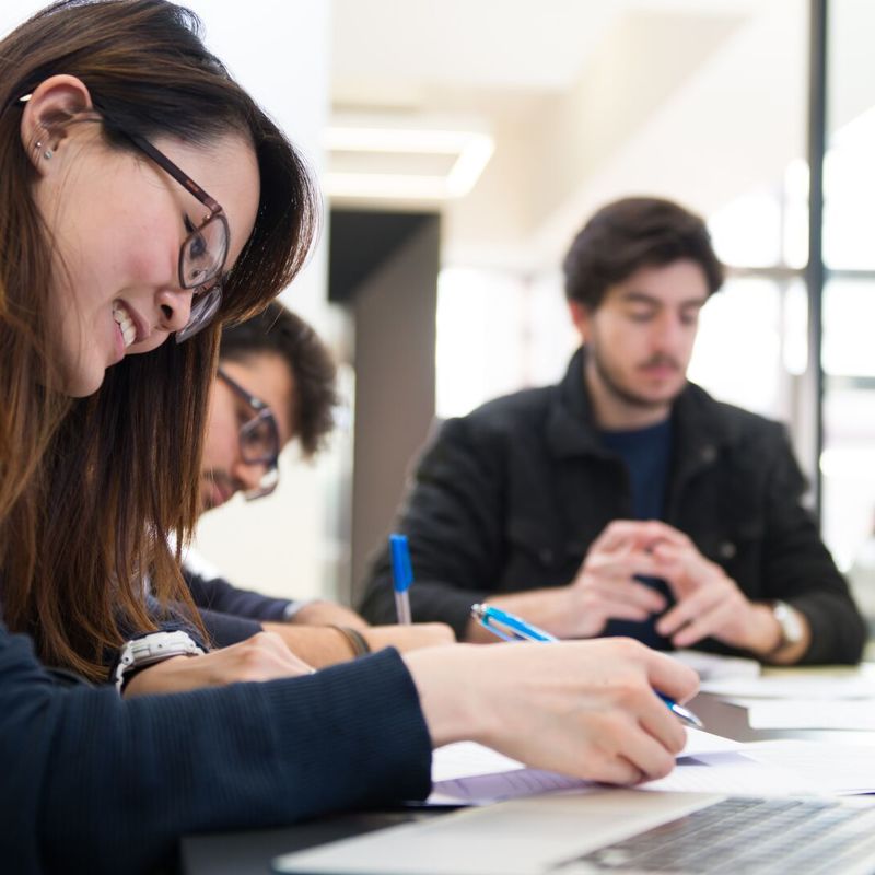 Masters students in front of laptop while working in university library