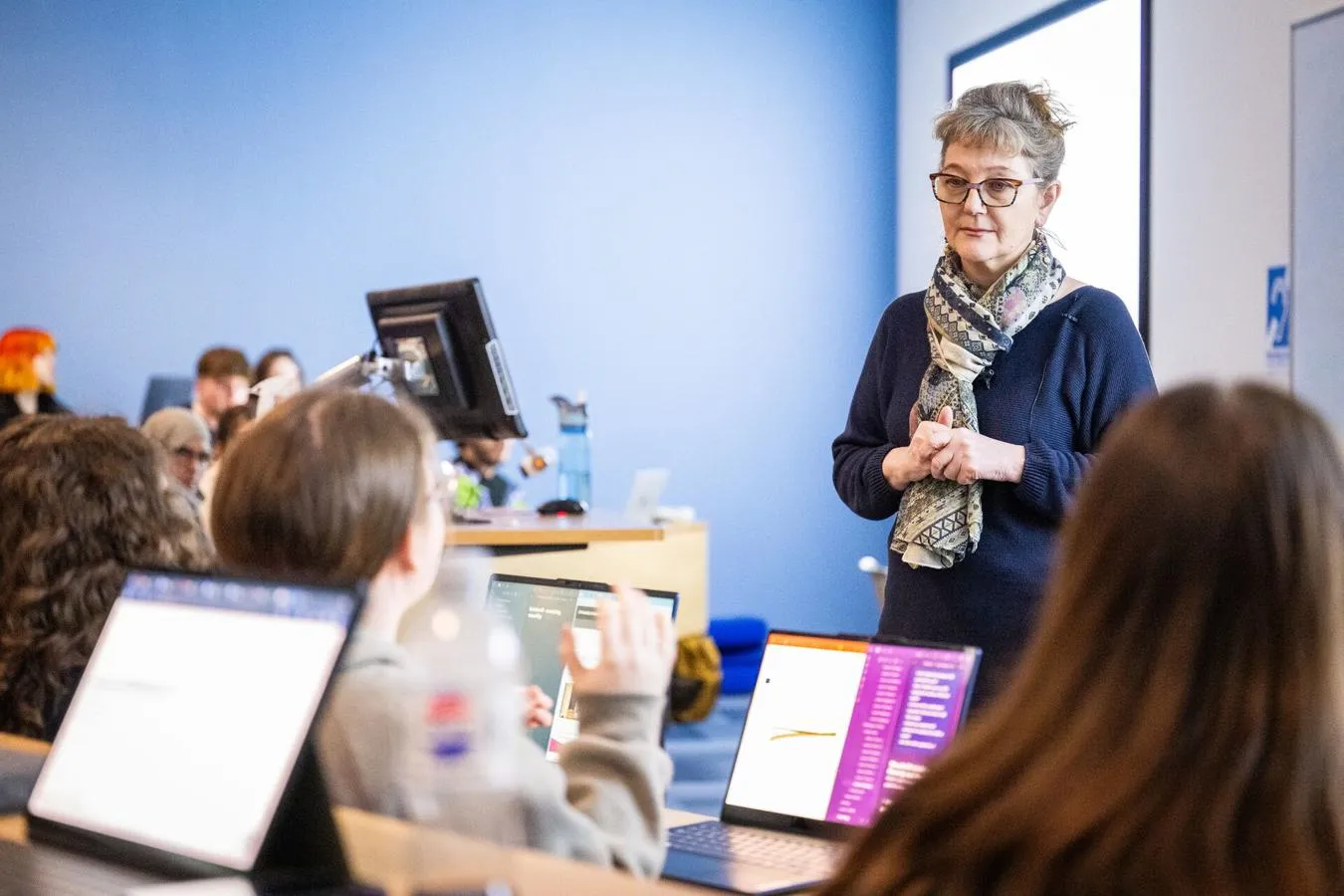 A lecturer listening to a group of students