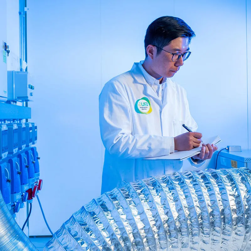 A researcher in a lab holding a pen and clipboard.