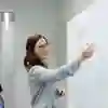A student teacher stood writing on a whiteboard