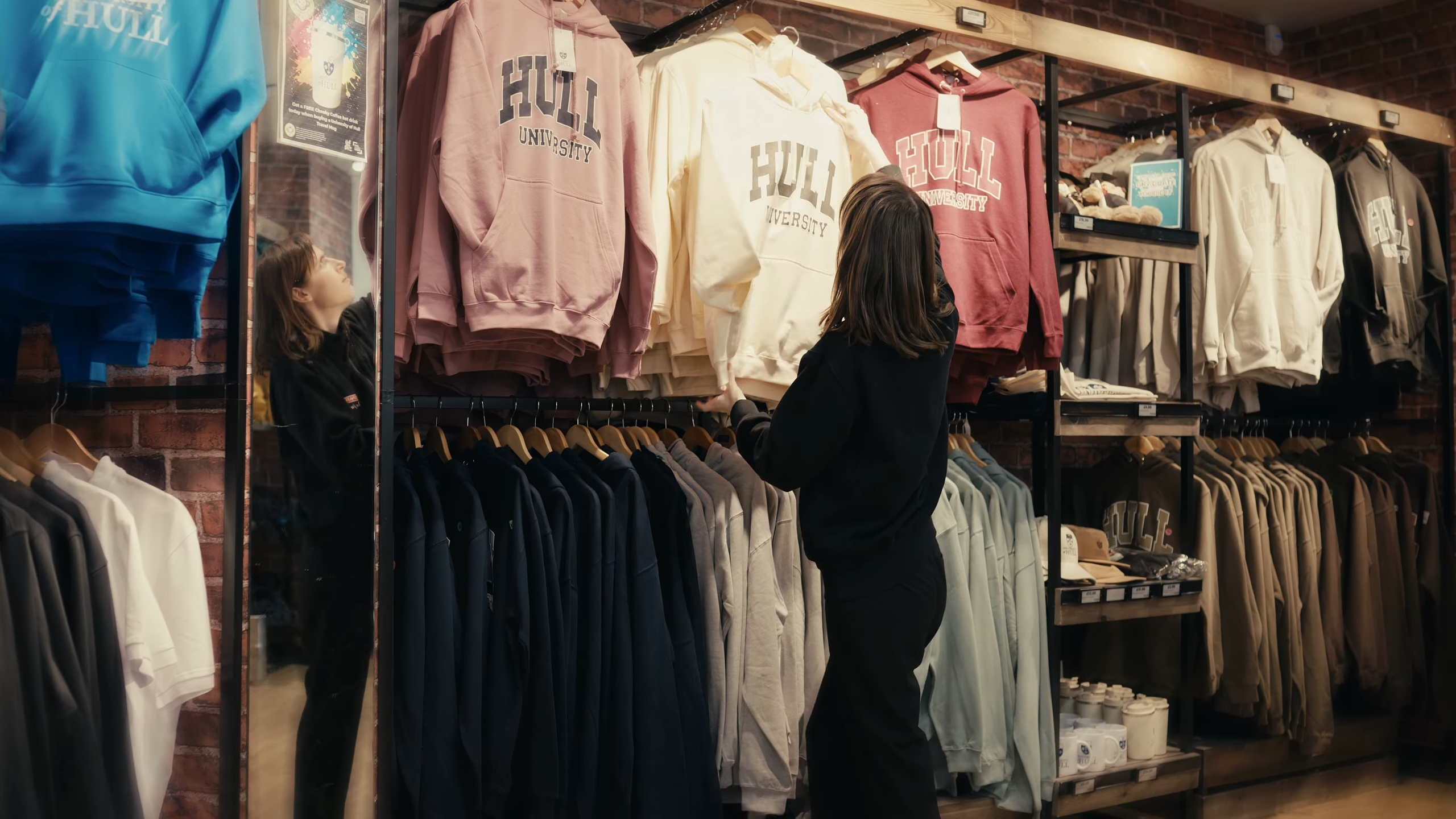 Person working in Spar on campus organising University of Hull sweatshirts.