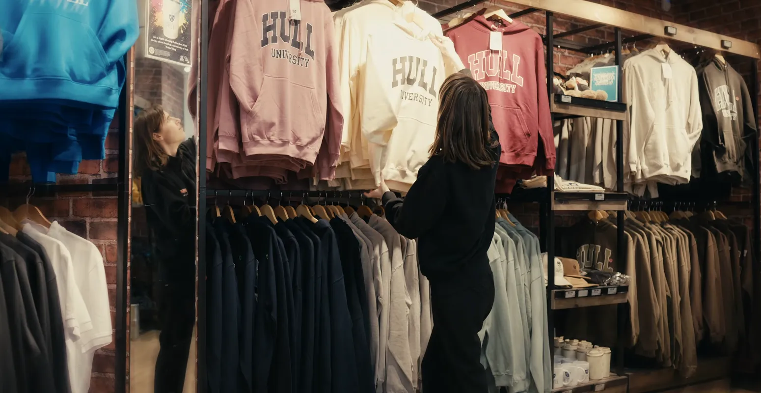 Person working in Spar on campus organising University of Hull sweatshirts.