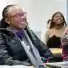 A group of students sitting in a lecture listening to a teacher at the front of the class