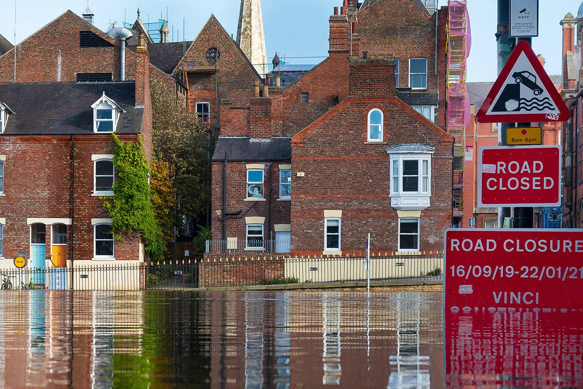 A flooded street with submerged road closed sign