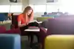 student reading books in a library seating area