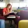 A student reads a book while seated in the university library