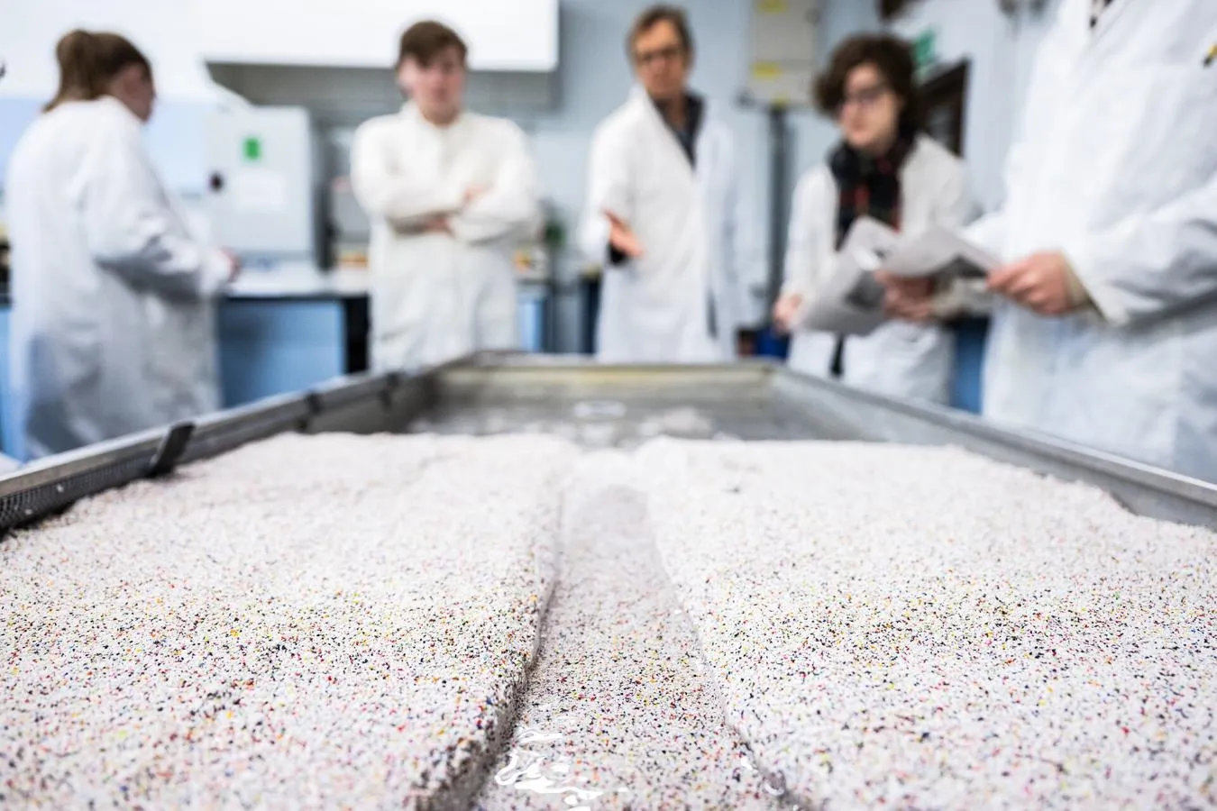 Channels of water running through sand in a box, simulating waterway currents in an experiment