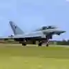 Jet fighter landing with brake parachute on airfield