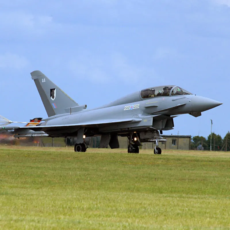 Jet fighter landing with brake parachute on airfield