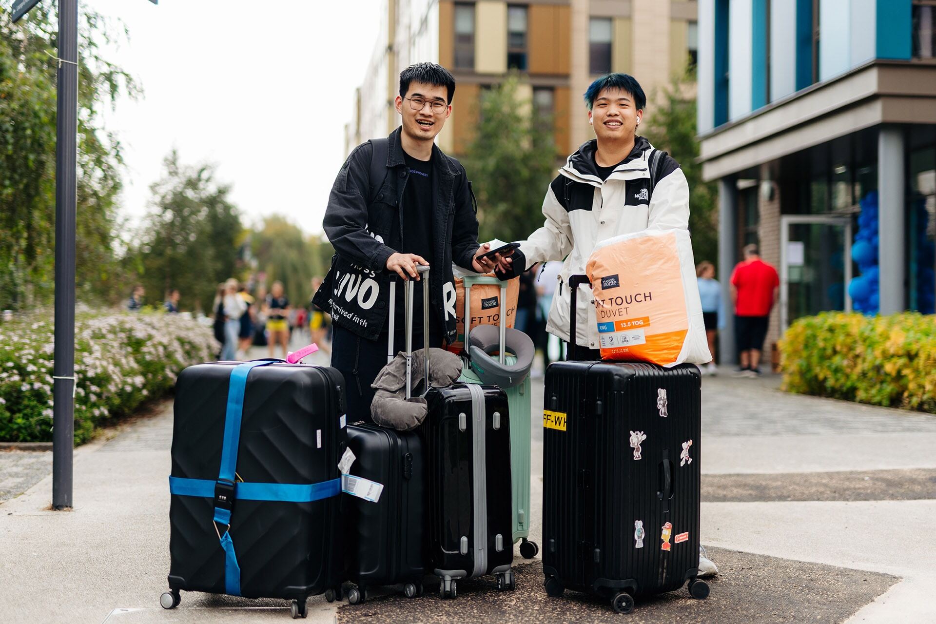 2 male students holding suitcases outside of their student accommodation