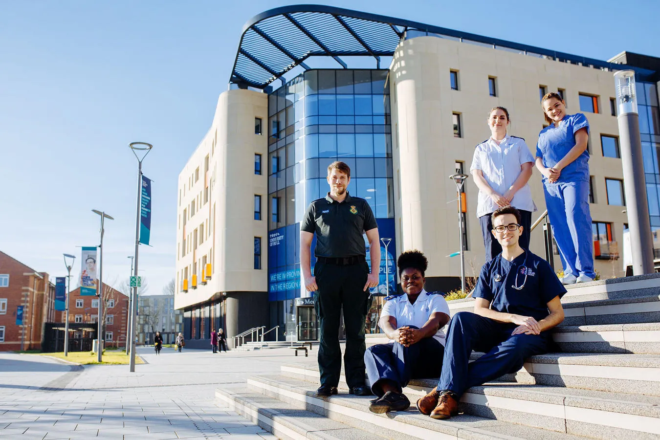 A group of students from different health courses stood outside the Allam Medical Building in uniform 
