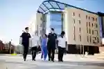 Health Students wearing a variety of NHS uniforms walking by the Allam Medical Building