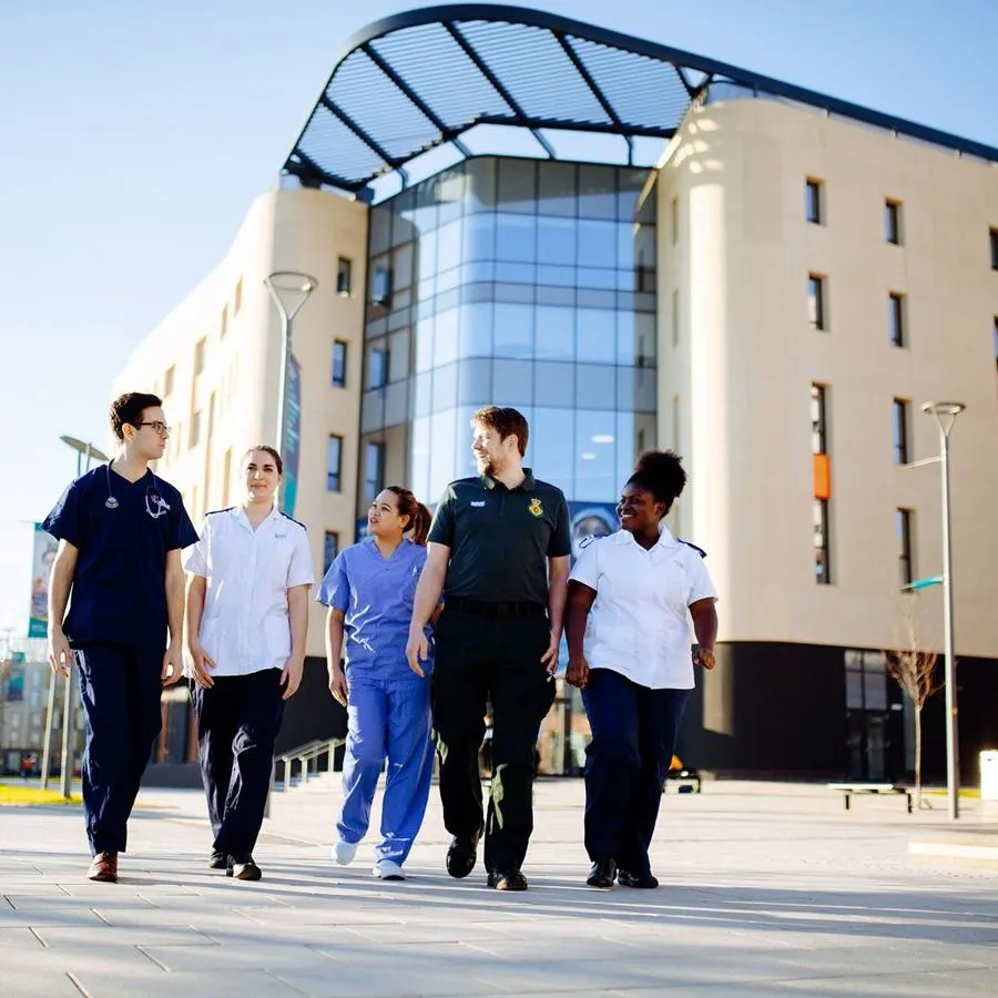 Health Students in NHS uniforms walking by the Allam Medical Building
