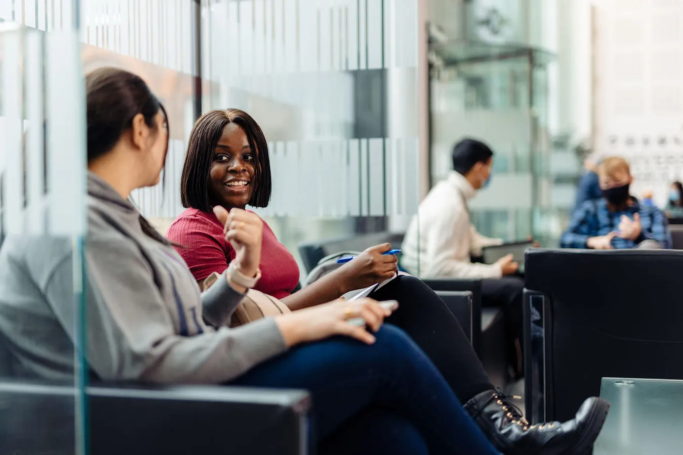 Students talk in a university foyer seating area