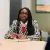 A law student wearing a checked blazer sitting at a desk making notes