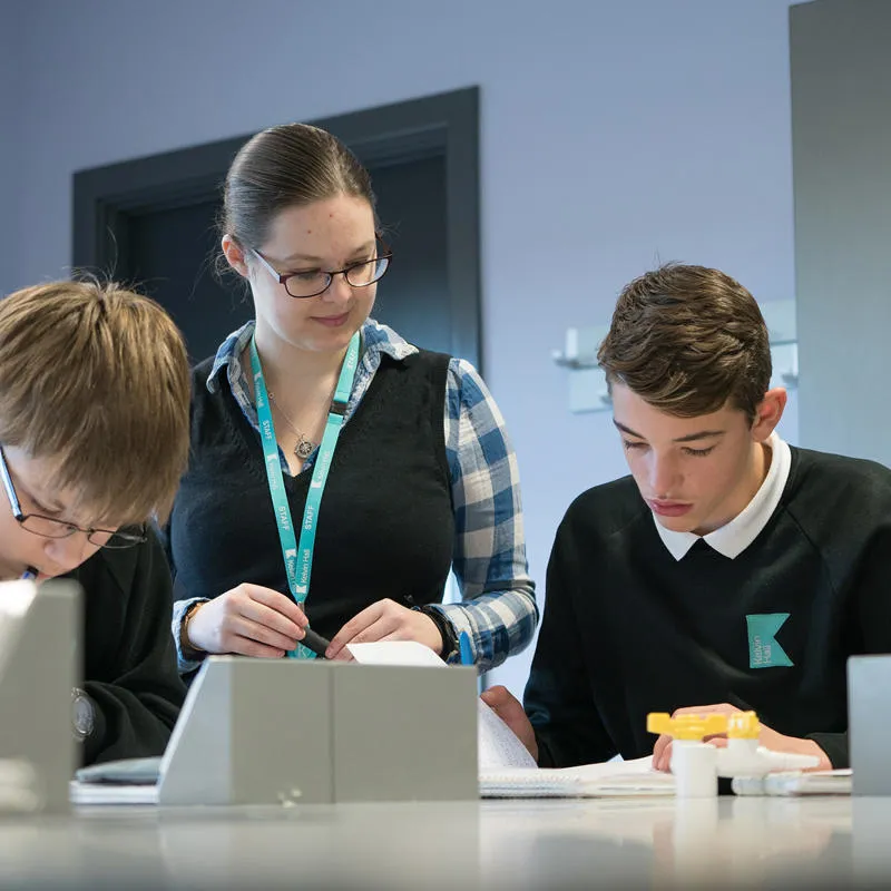 A teacher working with two students in a science lab at Kelvin School