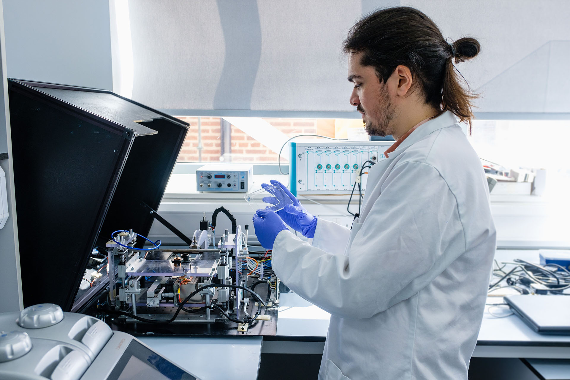 A man in a lab coat operates a complex machine in a laboratory setting.