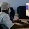 Student waring a beanie hat sitting at a desk working on a high speed computer