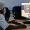 Student waring a beanie hat sitting at a desk working on a high speed computer