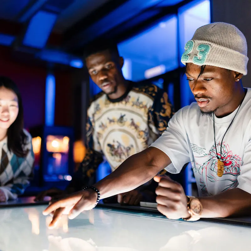 A young man in a beanie hat points to a screen in the Engineering Swift Additive Manufacturing Space.