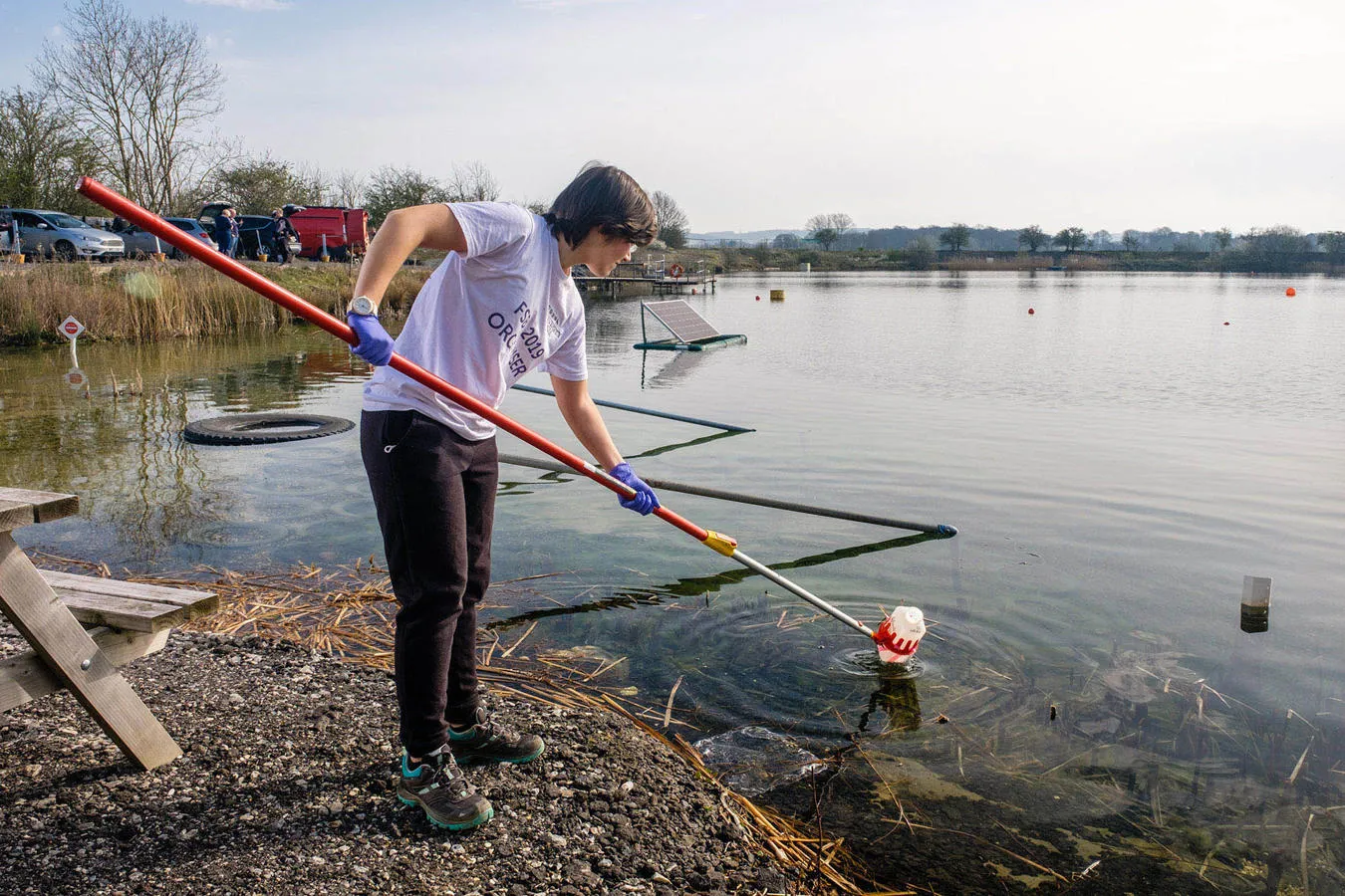 A PhD student taking water samples from a lake using a piece of equipment