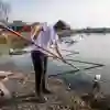 A PhD student taking water samples from a lake using a piece of equipment