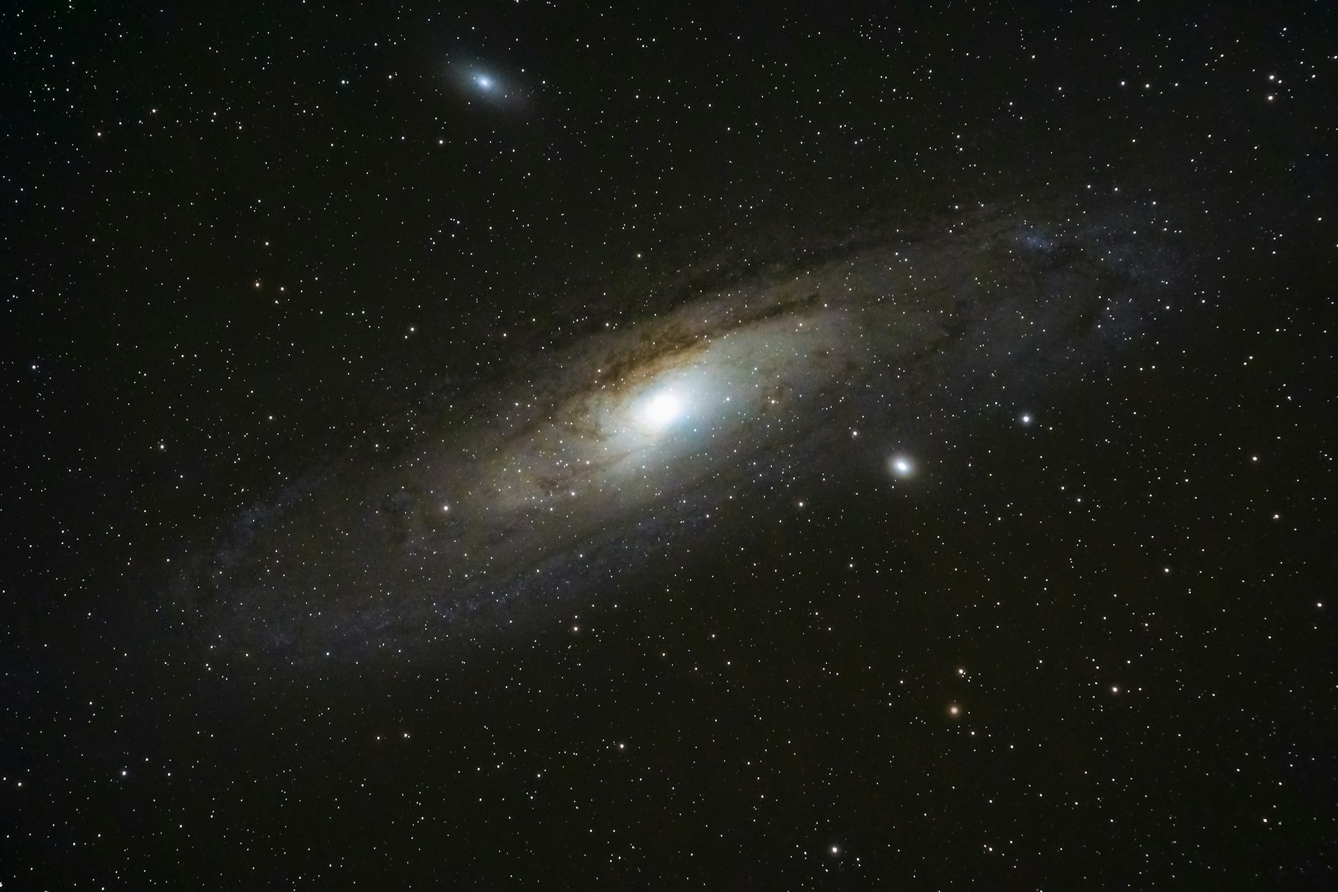 The Andromeda Galaxy - a bright star surrounded by an oval of swirling gases in a black night sky