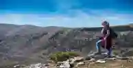 Student with backpack stands on sunny hilltop