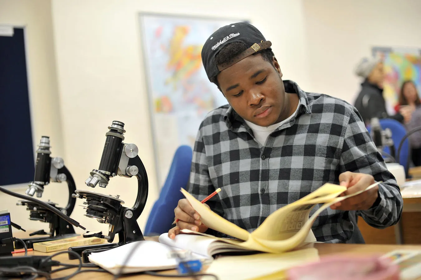 Geology student reading papers next to a microscope