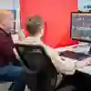 A lecturer and student looking at a computer monitor in the media hub