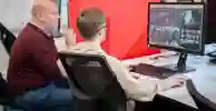 A lecturer and student looking at a computer monitor in the media hub