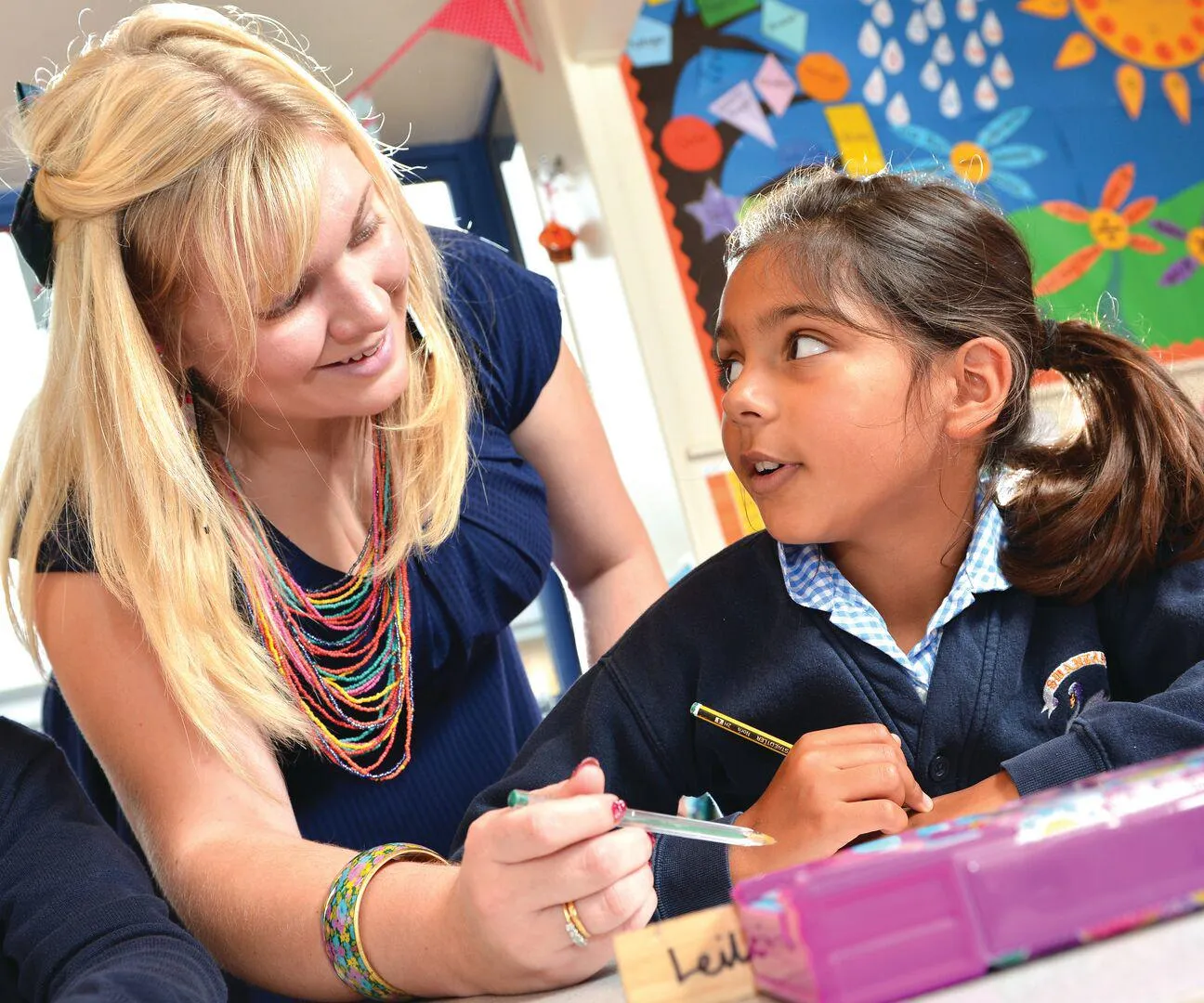 A PGCE teaching student working with two children on placement at Swanland Primary School