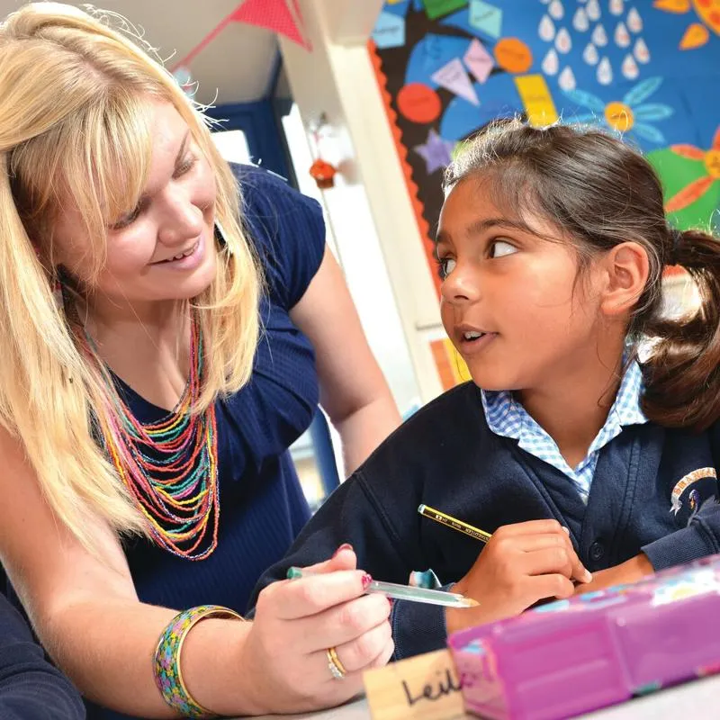 A teacher leaning over a student assessing her work