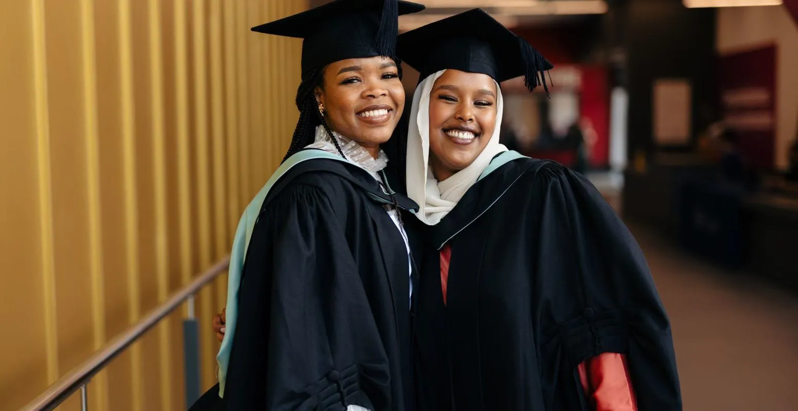 Two female students posing in their graduation cap and gowns