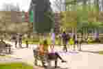 Students walking around a sunny campus with two people sitting on a bench in the foreground