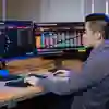 An accounting and financial management student works on a computer with stocks and shares on the screen