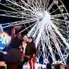 A group of students taking a selfie infront of an illuminated ferris wheel at night