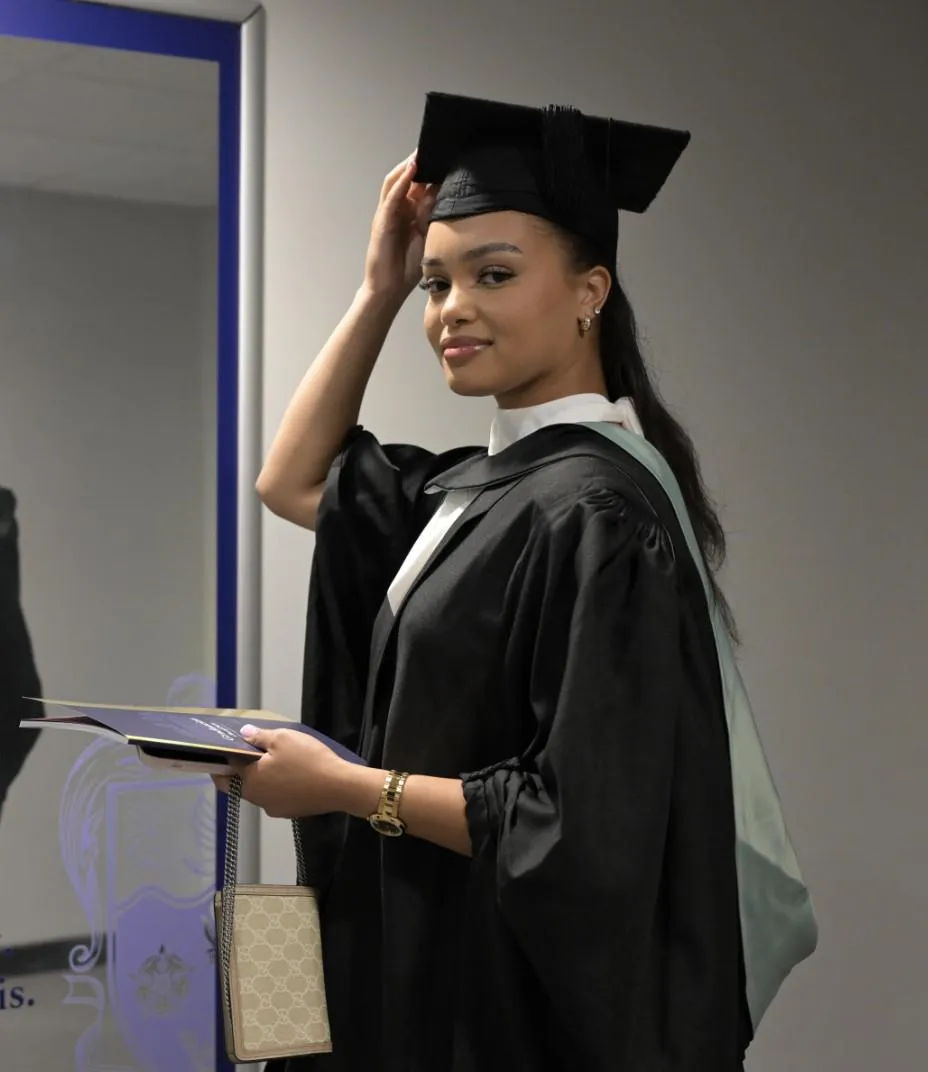 Female University of Hull graduate wearing a black cap and gown