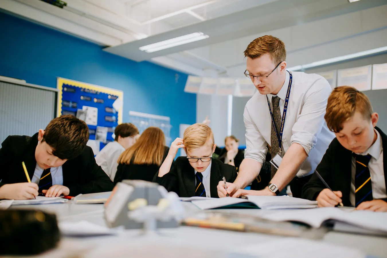 Teacher teaching a group of students at a desk