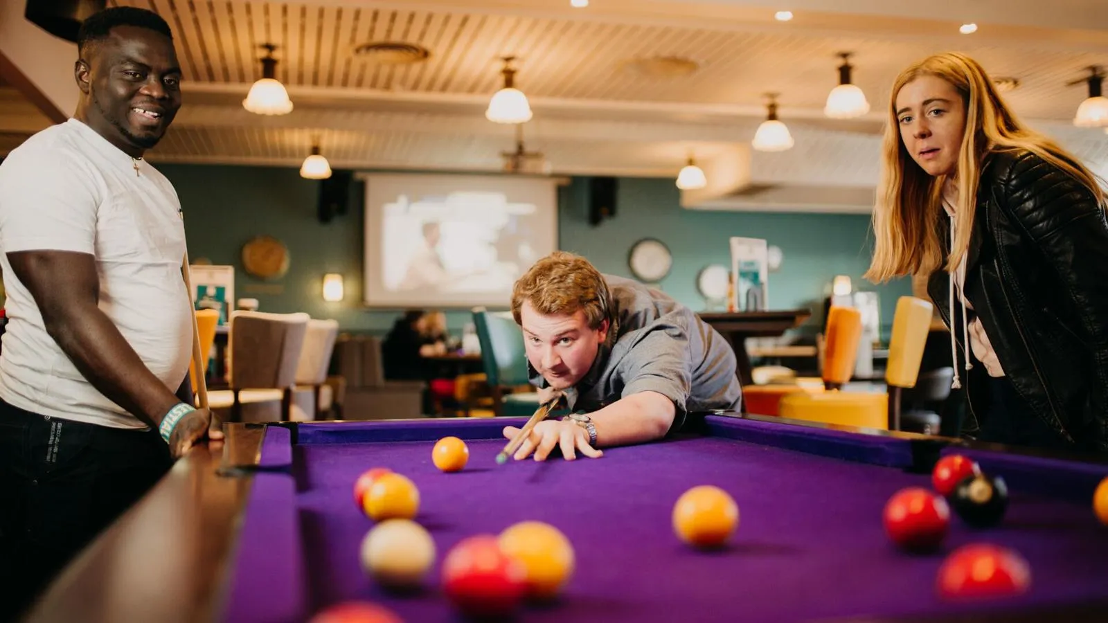 3 students playing a game of pool in the students' union