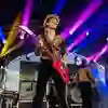Leopard print dressed guitarist plays big red electric guitar.