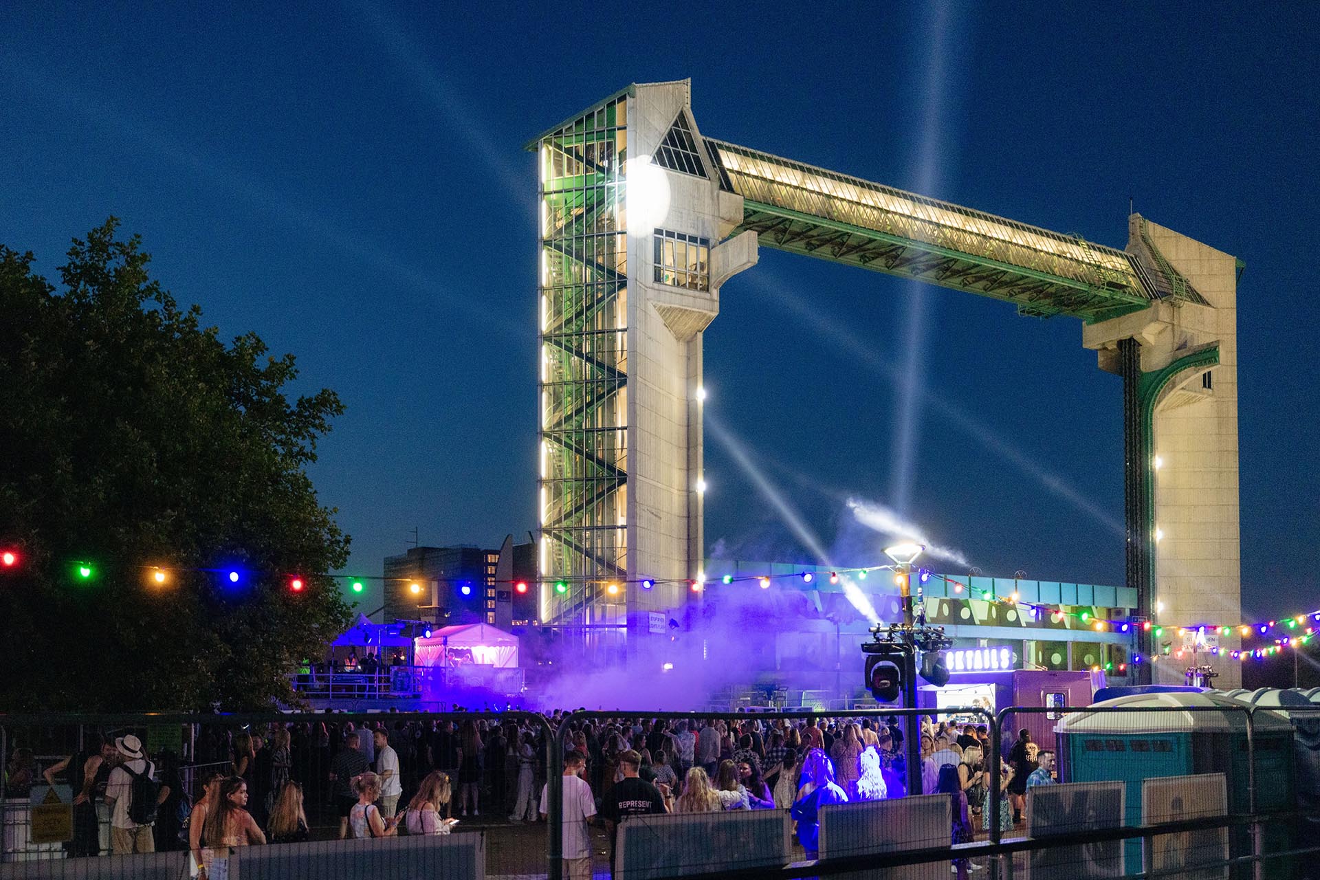 a music festival at night with the Hull tidal barrier in the background
