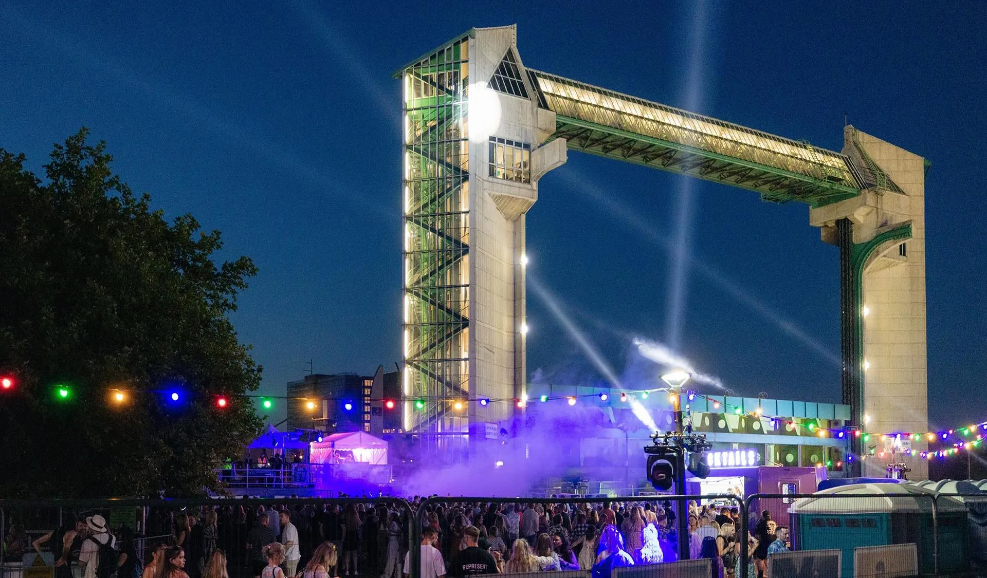 a music festival at night with the Hull tidal barrier in the background