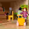 A peg doll and yellow toy pram in a dollhouse