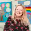An education student in a classroom with a colourful wall display behind her