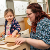 A student helping a child with wooden toys
