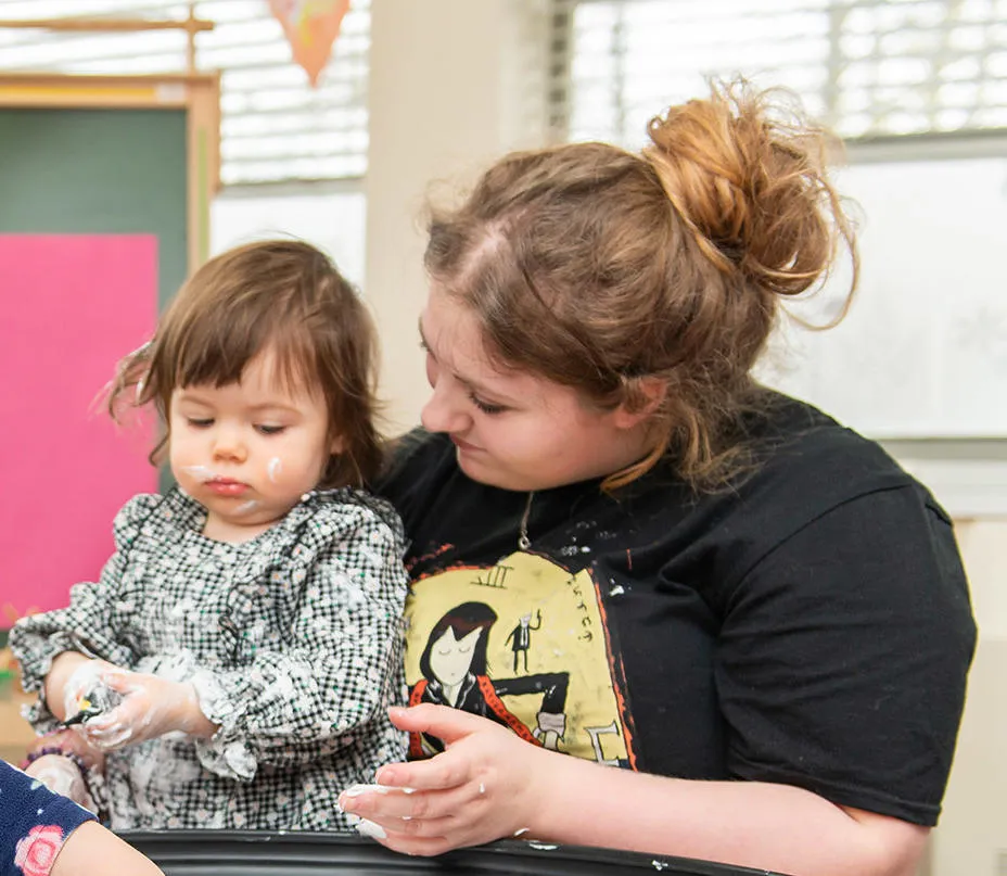 A student teacher playing with children in early years education space