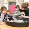 A student teacher playing with children in early years education space
